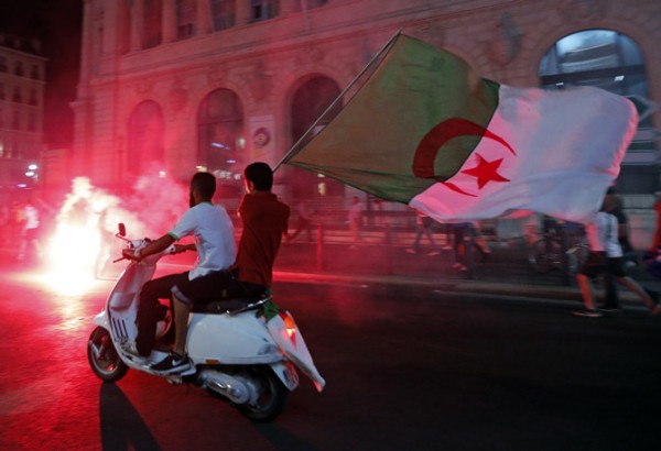 Algerian soccer fans hold their national flags as they celebrate after the end of Algeria's 2014 World Cup Group H match against Russia, in Marseille