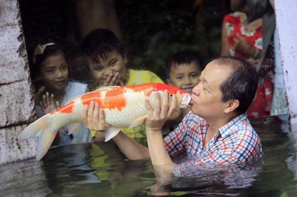 Zoo owner gives a kiss to a giant Japanese Koi carp while children watch, as part of the zoo's newest attraction dubbed "The World of Kois", in Malabon city