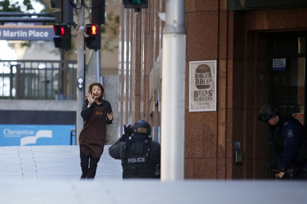 A hostage runs towards a police officer outside Lindt cafe, where other hostages are being held, in Martin Place in central Sydne