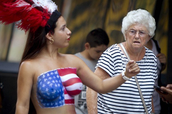 A woman walks past a woman who poses for tips wearing body paint and underwear  in Times Square in New York