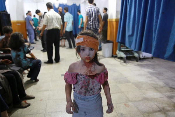 A wounded Syrian girl stands in a makeshift hospital in the rebel-held area of Douma, east of Syria’s capital of Damascus, following shelling and air raids by Syrian government forces on August 22, 2015. At least 20 civilians were killed, and another 200 wounded or trapped in Douma, a monitoring group said, just six days after regime airstrikes killed more than 100 people and sparked international condemnation of one of the bloodiest government attacks in Syria's war. (Abd Doumany / AFP / Getty)