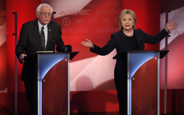 Bernie Sanders listens as Hillary Clinton speaks. REUTERS/Mike Segar