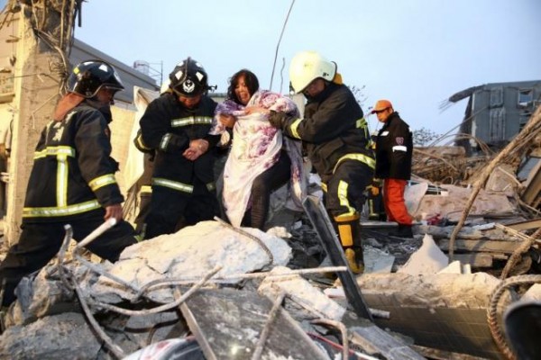 Rescue personnel help a victim at a damaged building after an earthquake in Tainan, southern Taiwan, February 6, 2016. REUTERS/Stringer