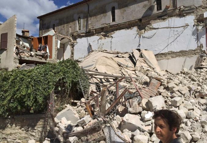 A woman stands in front of a collapsed house following an earthquake in Accumuli di Rieti, central Italy, August 24, 2016. REUTERS/Steve Scherer