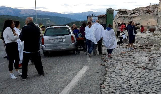 People stand along a road following a quake in Amatrice, central Italy, August 24, 2016. REUTERS/Emiliano Grillotti