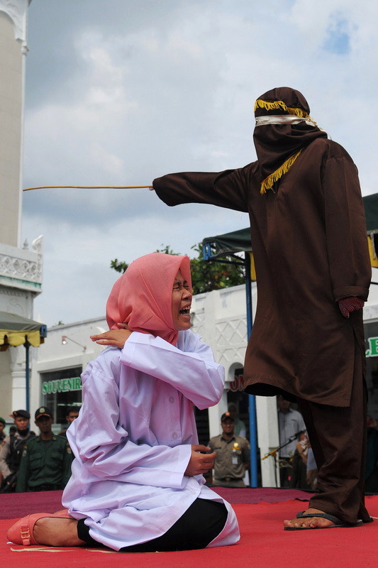 A young Acehnese woman (L) is caned in public, a punishment under the Islamic sharia law, under the offence of "khalwat" or "close proximity" between a man and a woman who are not spouses, in Banda Aceh on December 28, 2015. Aceh is the only province of Indonesia enforcing the Islamic Sharia law and offenders are punished by public caning. / AFP / Chaideer Mahyuddin (Photo credit should read CHAIDEER MAHYUDDIN/AFP/Getty Images)