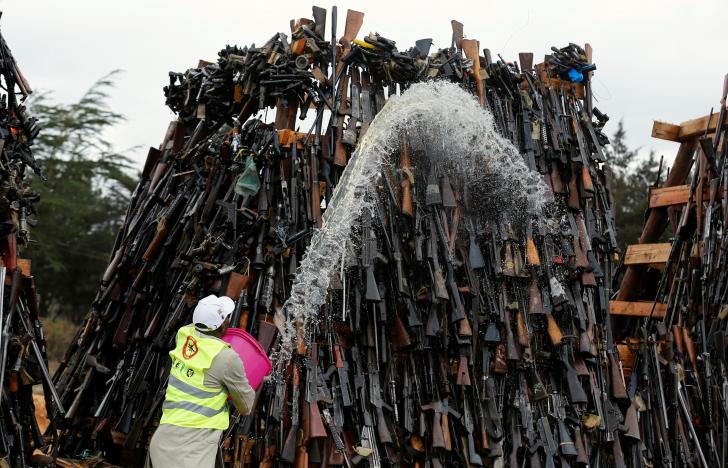 A worker pours fuel on an assortment of guns during a public burning of 5250 illicit firearms and small weapons, recovered during various security operations in Ngong hills near Kenya's capital Nairobi, November 15, 2016. REUTERS/Thomas Mukoya
