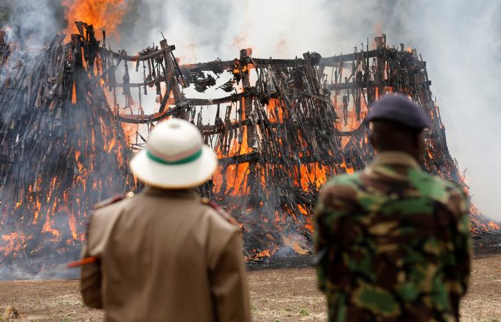 A policeman and a local administration official watch as an assortment of 5250 illicit firearms and small weapons, recovered during various security operations burns during its destruction in Ngong hills near Kenya's capital Nairobi, November 15, 2016. REUTERS/Thomas Mukoya